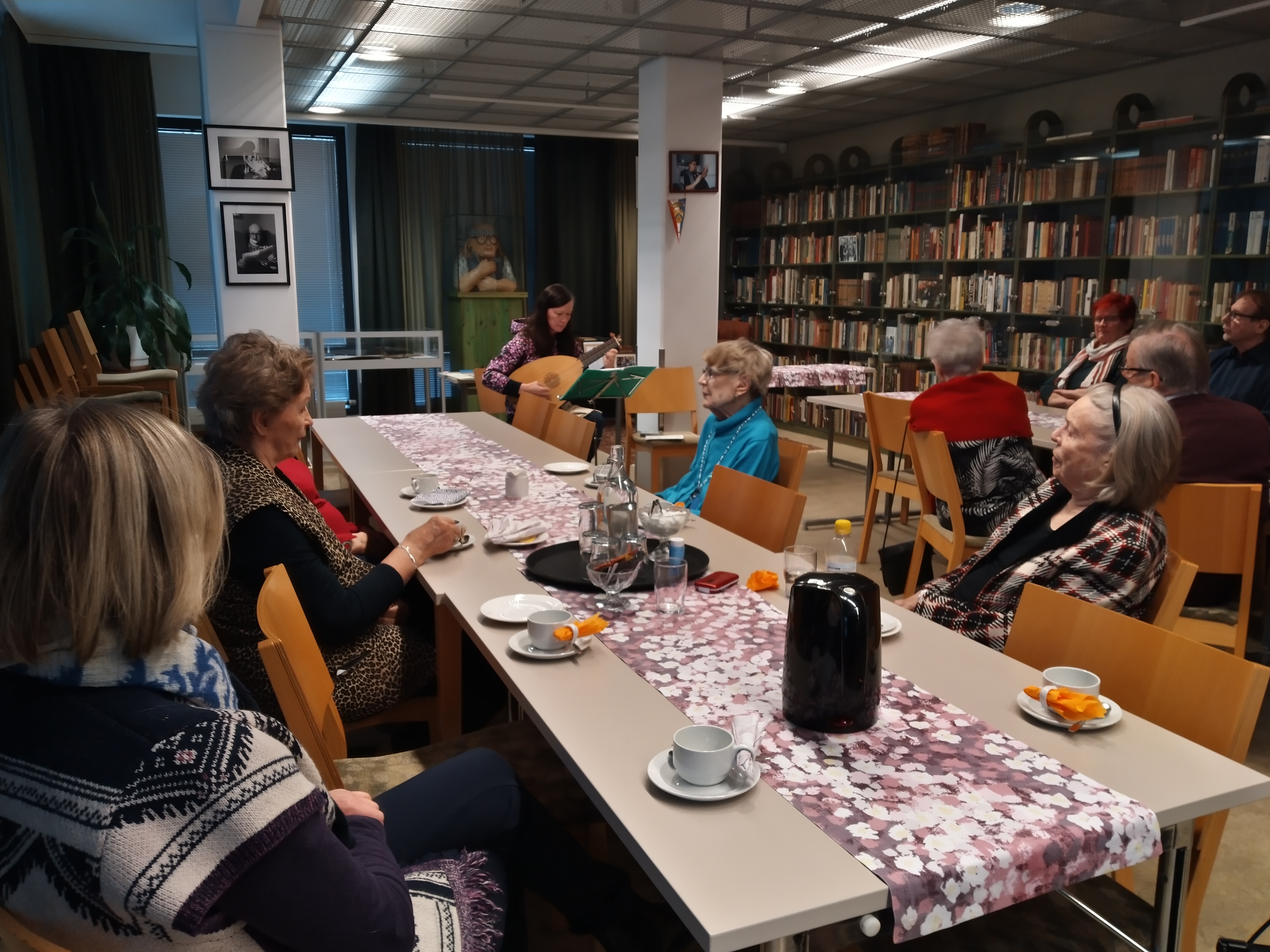 Kuvassa senioritalon asukkaat kuuntelevat tuutorin luutun soittoa.