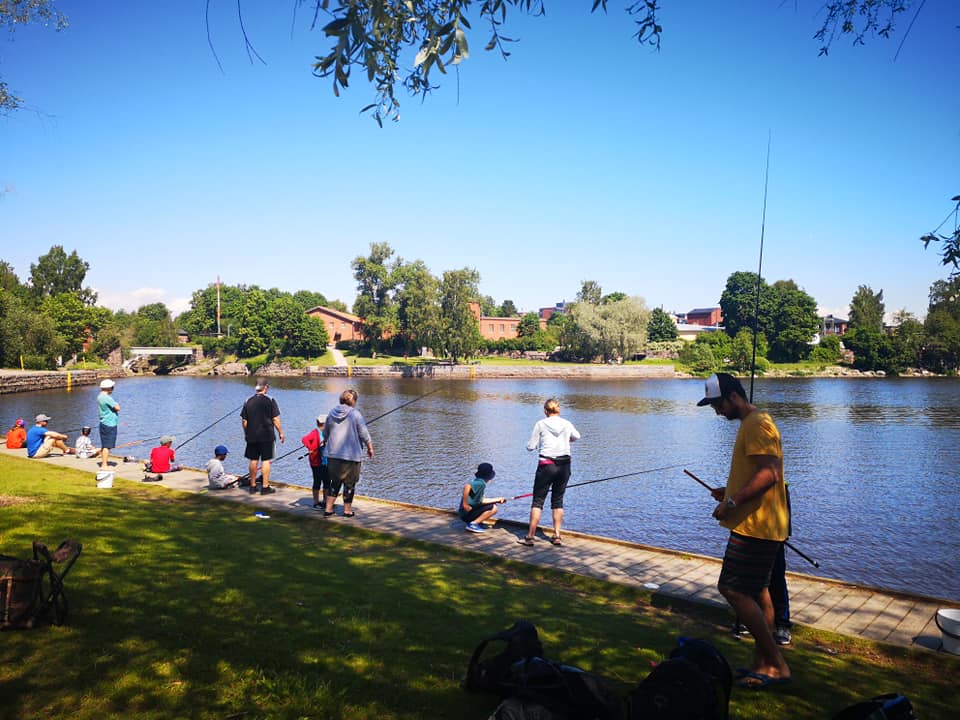 Kuvassa lapset ja vapaaehtoiset mieskaverit kalastavat rannalla.