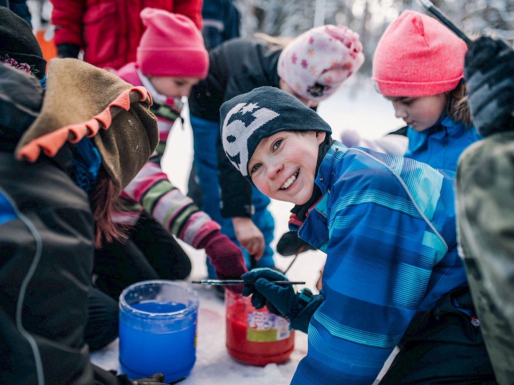 Kuvassa talvileiriläisiä askartelemassa ulkona lumessa.