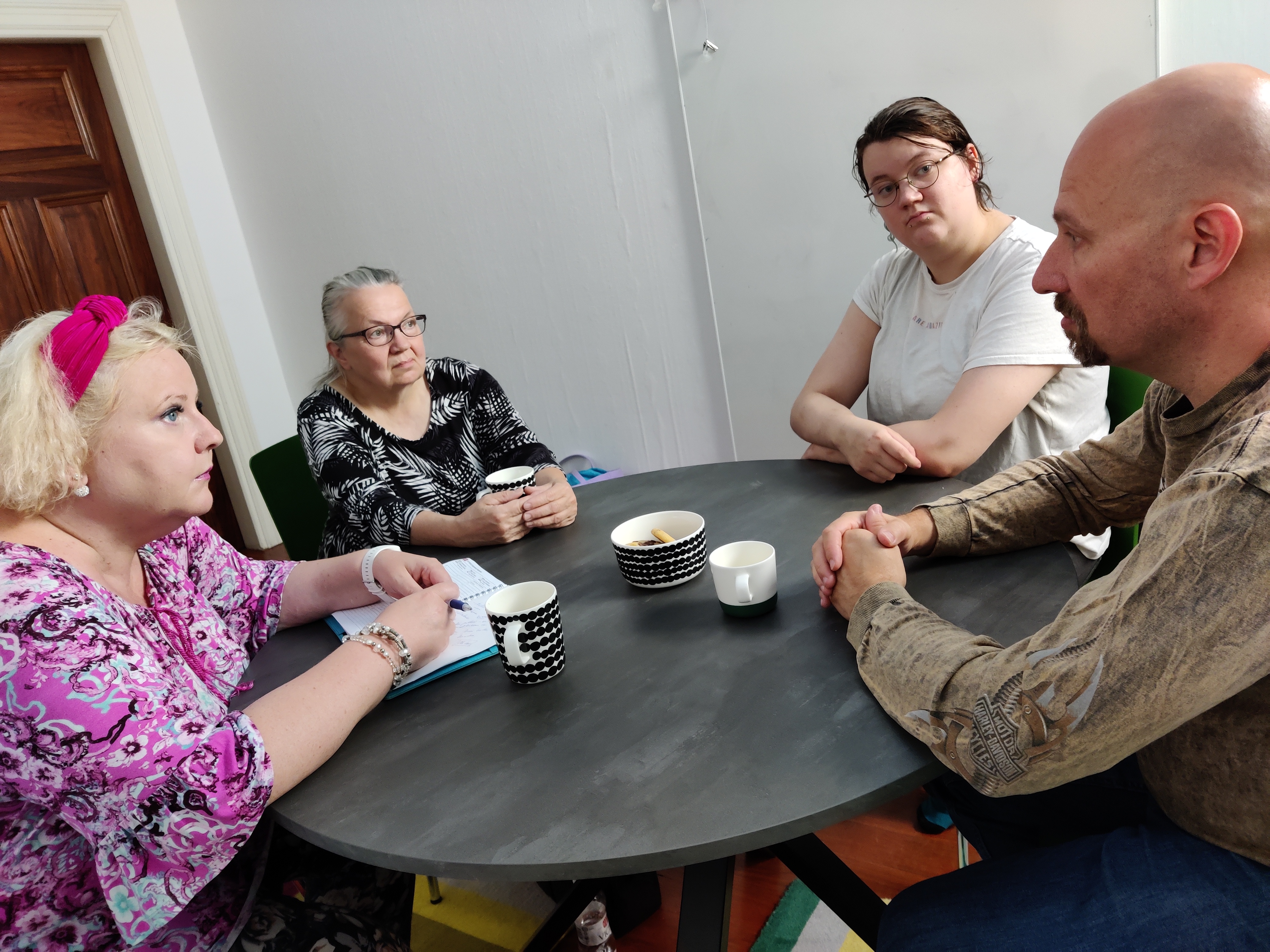 Neljä henkilöä istuu pöydän ääressä keskustelemassa.